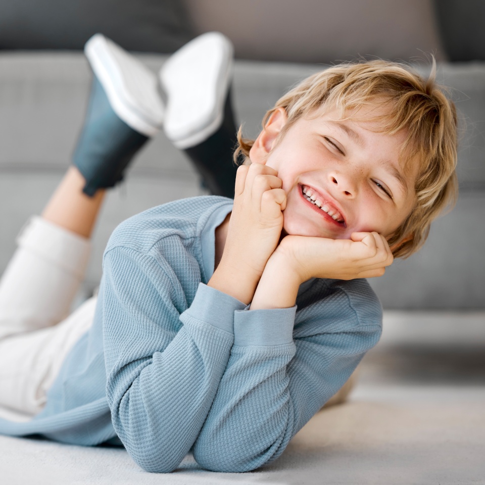 Happy kid, boy portrait and relax in home for security, weekend fun or chill in living room. Smile, young child or excited on floor for dental care, development or healthy teeth for growth in morning