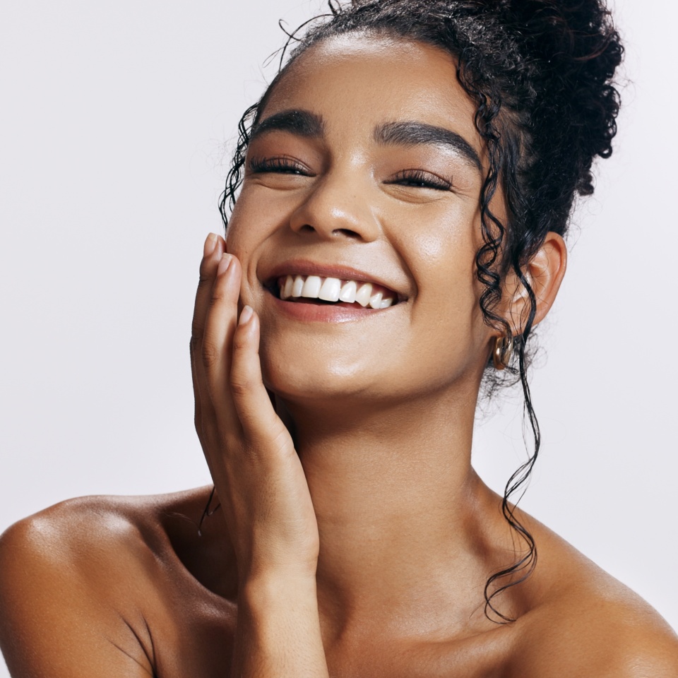 Studio, shine and portrait of woman, touch and treatment of skincare, soft and glow of body in results. Pink background, face and proud for skin, dermatology and cosmetics for person and hand